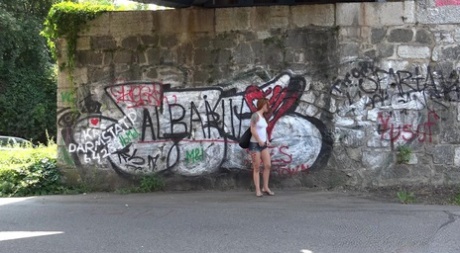 Redheaded girl Foxie T takes a pee under an overpass during the day 91917018